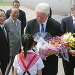 Former president Bill Clinton receiving a bouquet of flowers upon his arrival at an airport in Pyongyang